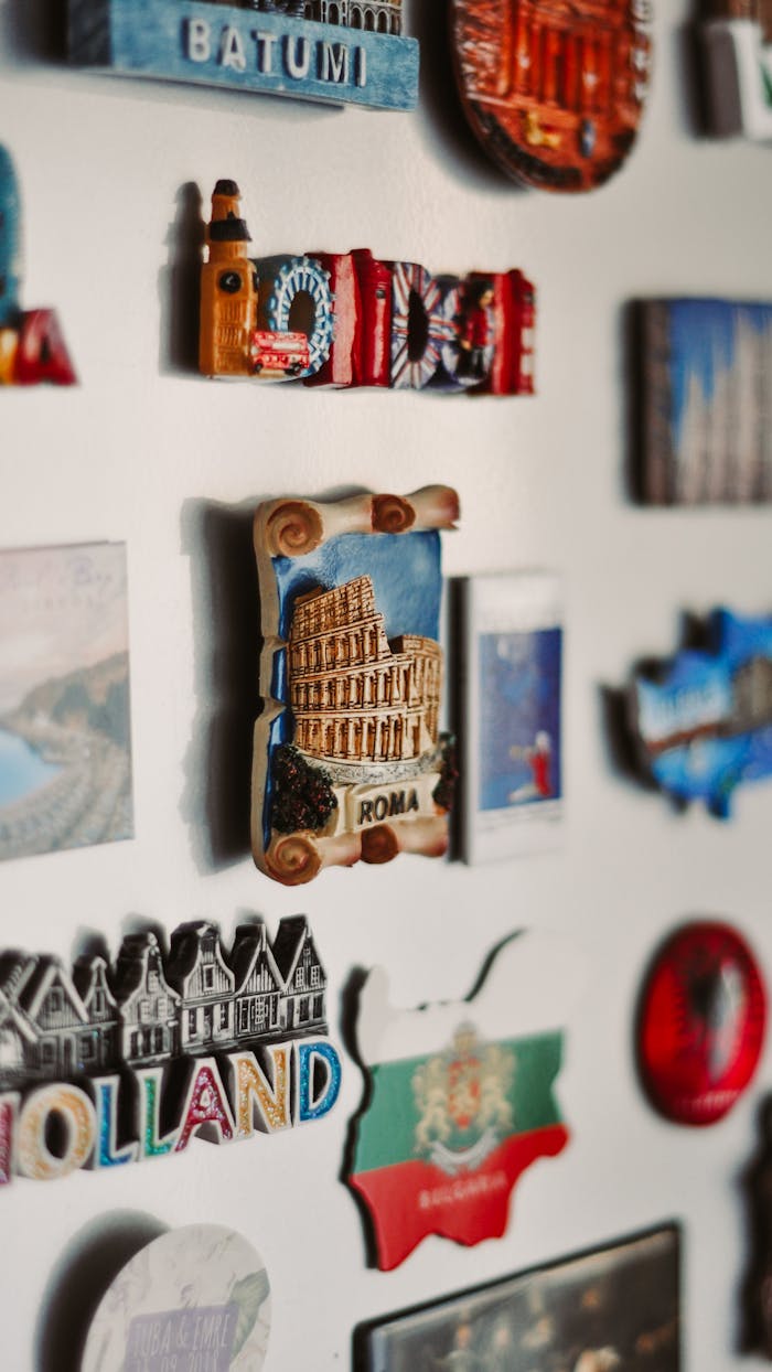 Full frame collection of assorted colorful magnets of different shapes attached on white refrigerator in light kitchen of modern apartment